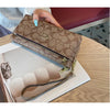 A brown patterned zipper wallet is shown being held by a hand, with cards and a leather strap visible.