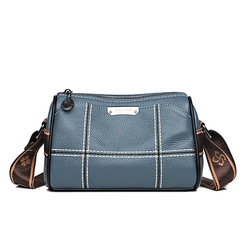 A slate blue luxury cowhide shoulder bag with brown leather trim and stitching.