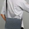 A woman wearing a striped shirt holds a gray patterned flap crossbody bag.