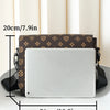 A brown leather crossbody bag with a flap design and a silver-colored laptop inside, shown on a white table.