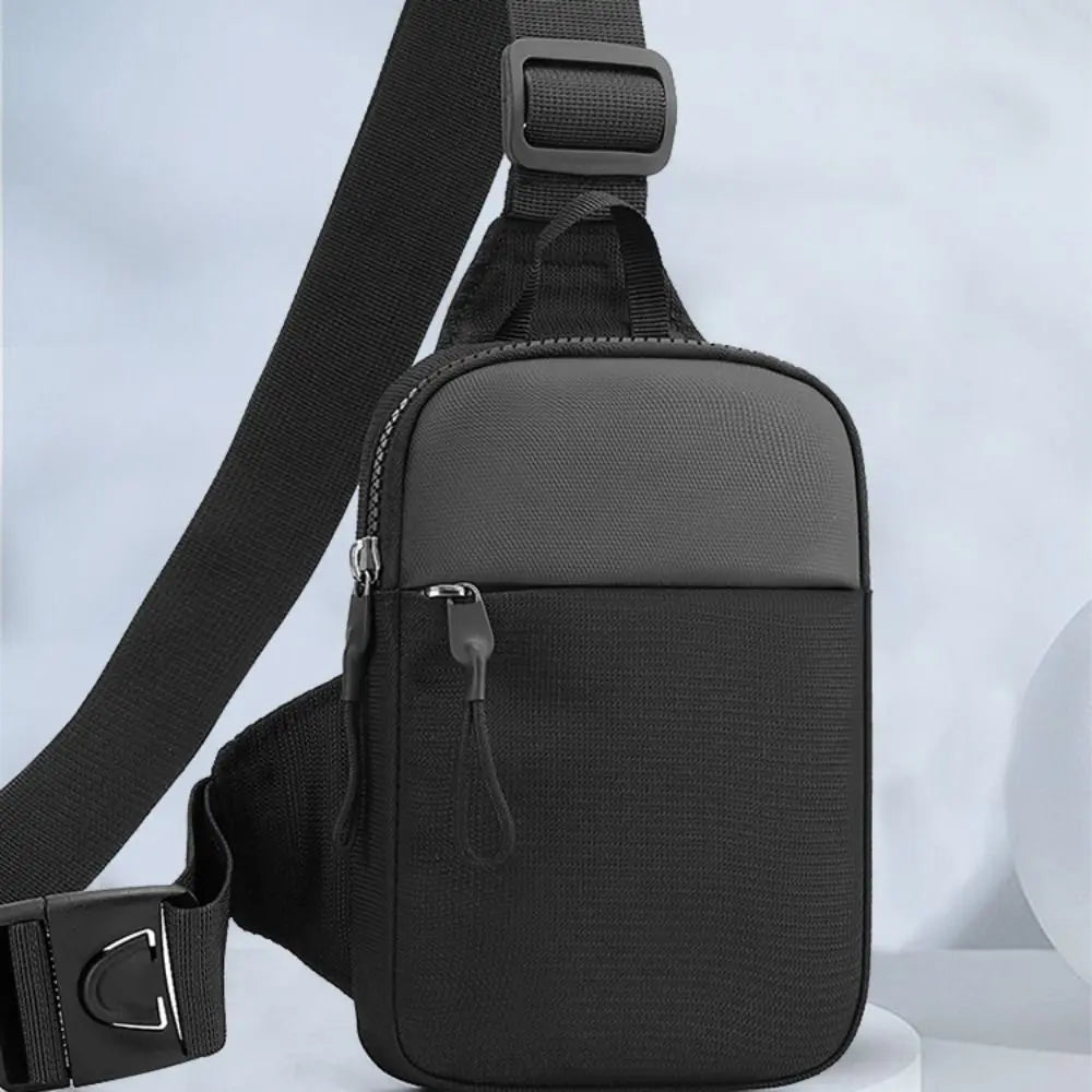 A black canvas crossbody sling bag with a padded strap and zipper detail.