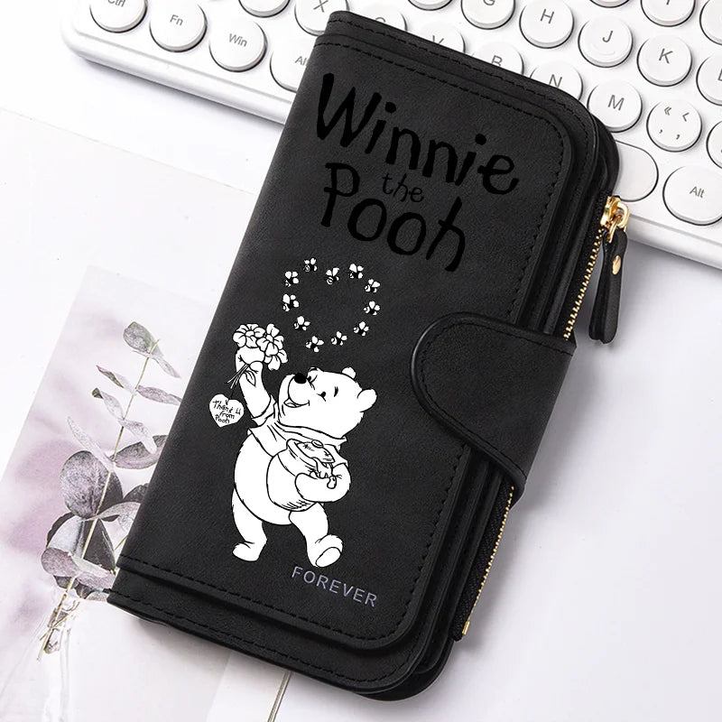 A black zippered pouch featuring a Winnie the Pooh design with a bear and flowers.