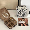 A leopard print PU leather jewelry storage box with a zippered pouch and velvet inserts is shown next to a matching zippered 