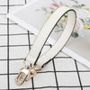 A beige leather replacement shoulder strap with a gold-toned clasp is displayed on a white and black checkered surface.