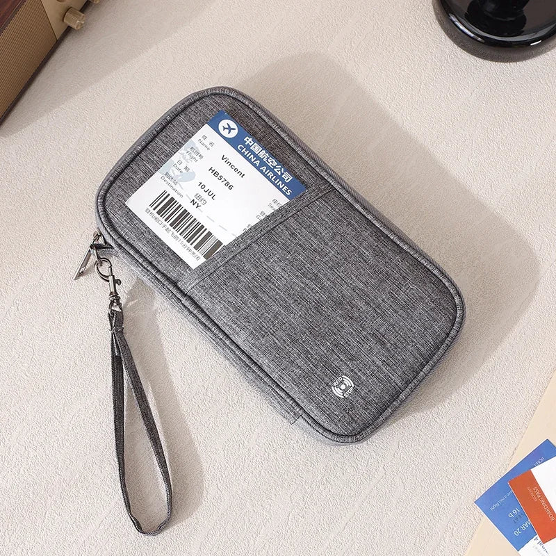 Cartera de pasaporte gris con bloqueador RFID y correa de cuero, mostrada sobre una superficie clara.