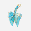 A light blue and white striped fabric bow attached to a gold chain strap extension for a handbag.