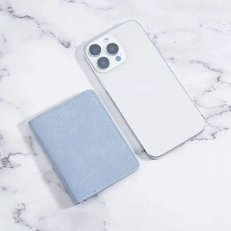 A white smartphone and a light blue card wallet are displayed on a marble surface.