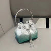 A silver crystal-embellished evening clutch bag with a chain strap resting on a gray surface.