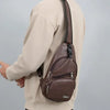 Une personne porte un sweat beige et tient un sac à bandoulière multifonction avec fermeture éclair en PU marron.