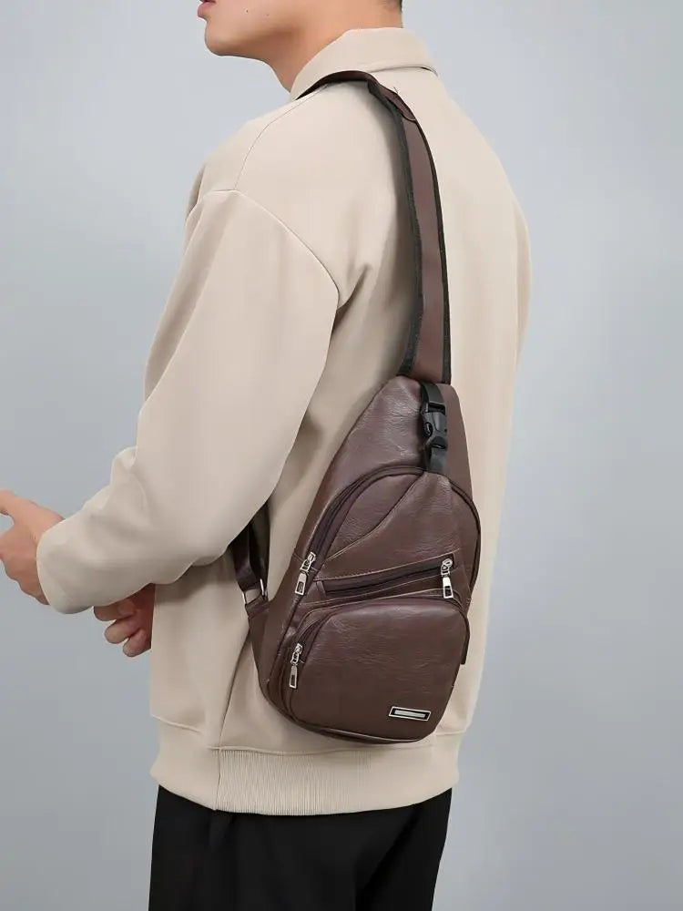 Une personne porte un sweat beige et tient un sac à bandoulière multifonction avec fermeture éclair en PU marron.
