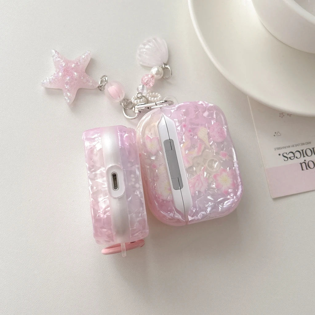 Étui d'écouteurs avec nœud floral rose pour AirPods à côté d'un charm en forme d'étoile.