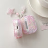 Étui d'écouteurs en nœud floral rose pour AirPods à côté d'un charm en forme d'étoile.