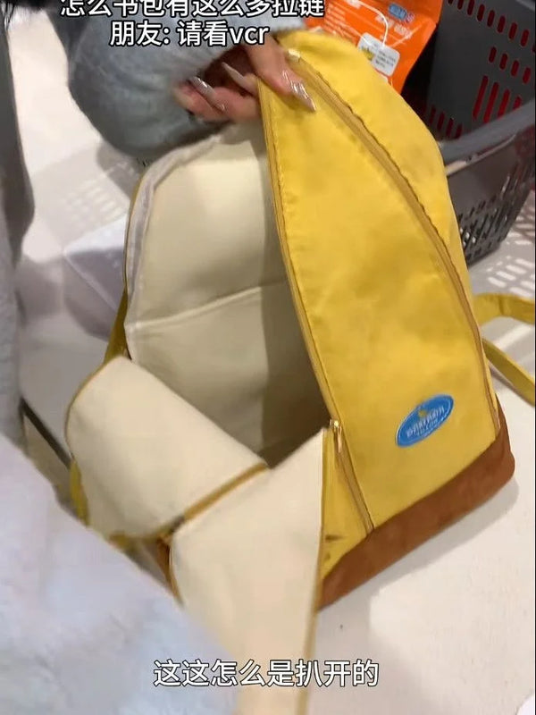 A yellow and brown banana-shaped backpack is shown open, displaying the interior lining.