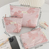 Pink bow knot cosmetic organizer bags displayed next to a smartphone and cosmetic tools.