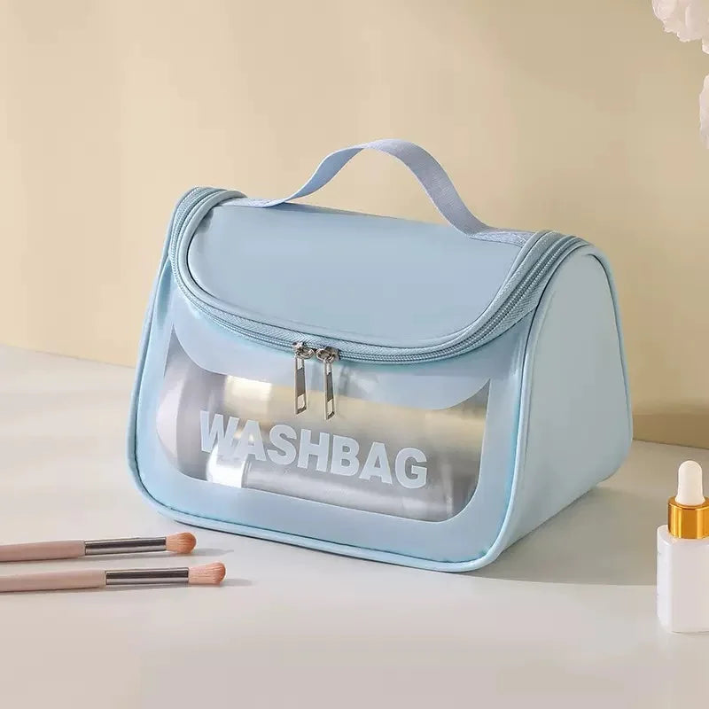 Sac à toilette transparent bleu clair et imperméable avec poignée, exposé sur une surface blanche.