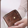 A brown genuine leather wallet is held in a hand against a light background.