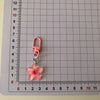 A pink resin flower charm attached to a silver keyring, measured against a ruler.