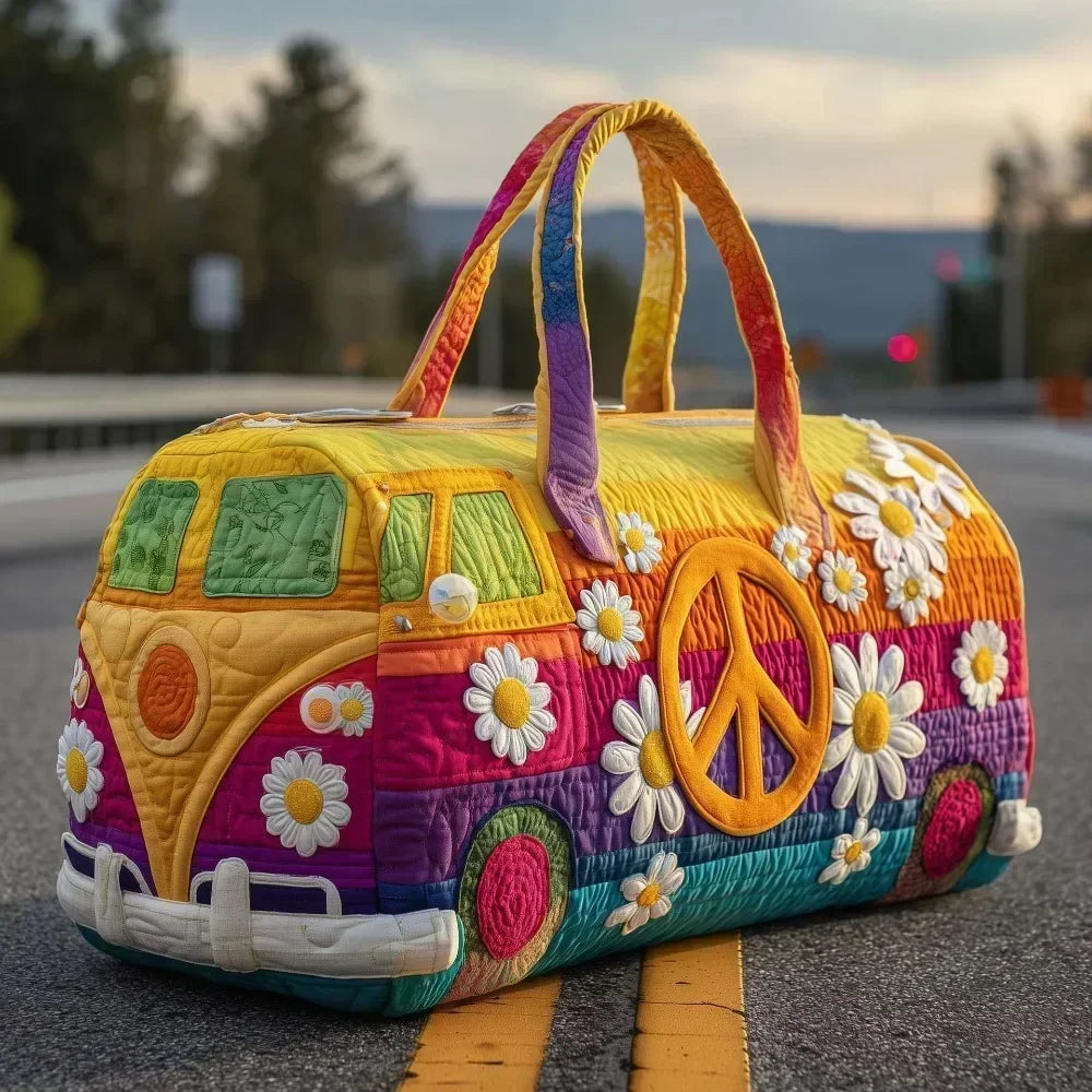 A yellow quilted travel duffle bag decorated with peace signs and floral patterns resting on asphalt.