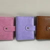 Three leather-bound notebooks in pink, purple, and brown with matching closures.