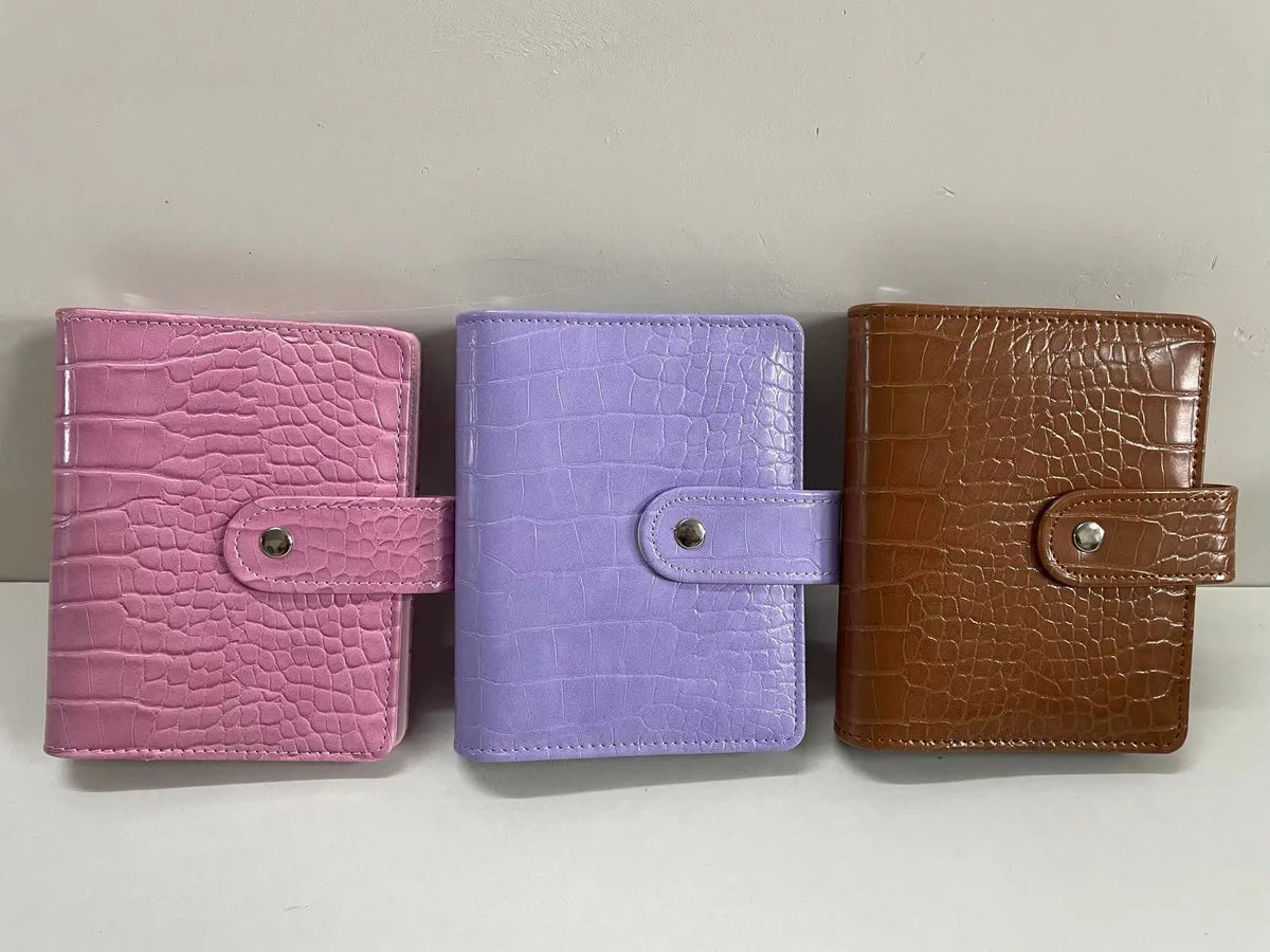 Three leather-bound notebooks in pink, purple, and brown with matching closures.