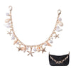 A delicate gold-toned necklace featuring pearl and starfish charms, displayed next to a black leather pouch.