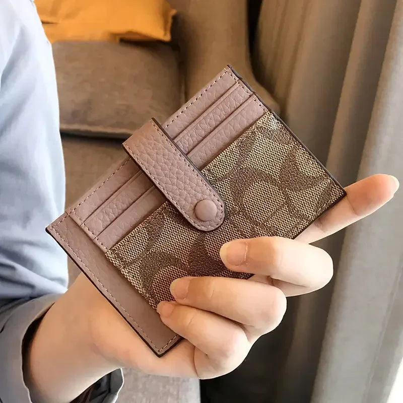 Une main tient un porte-cartes en cuir PU brun et fin à motif texturé sur fond clair.