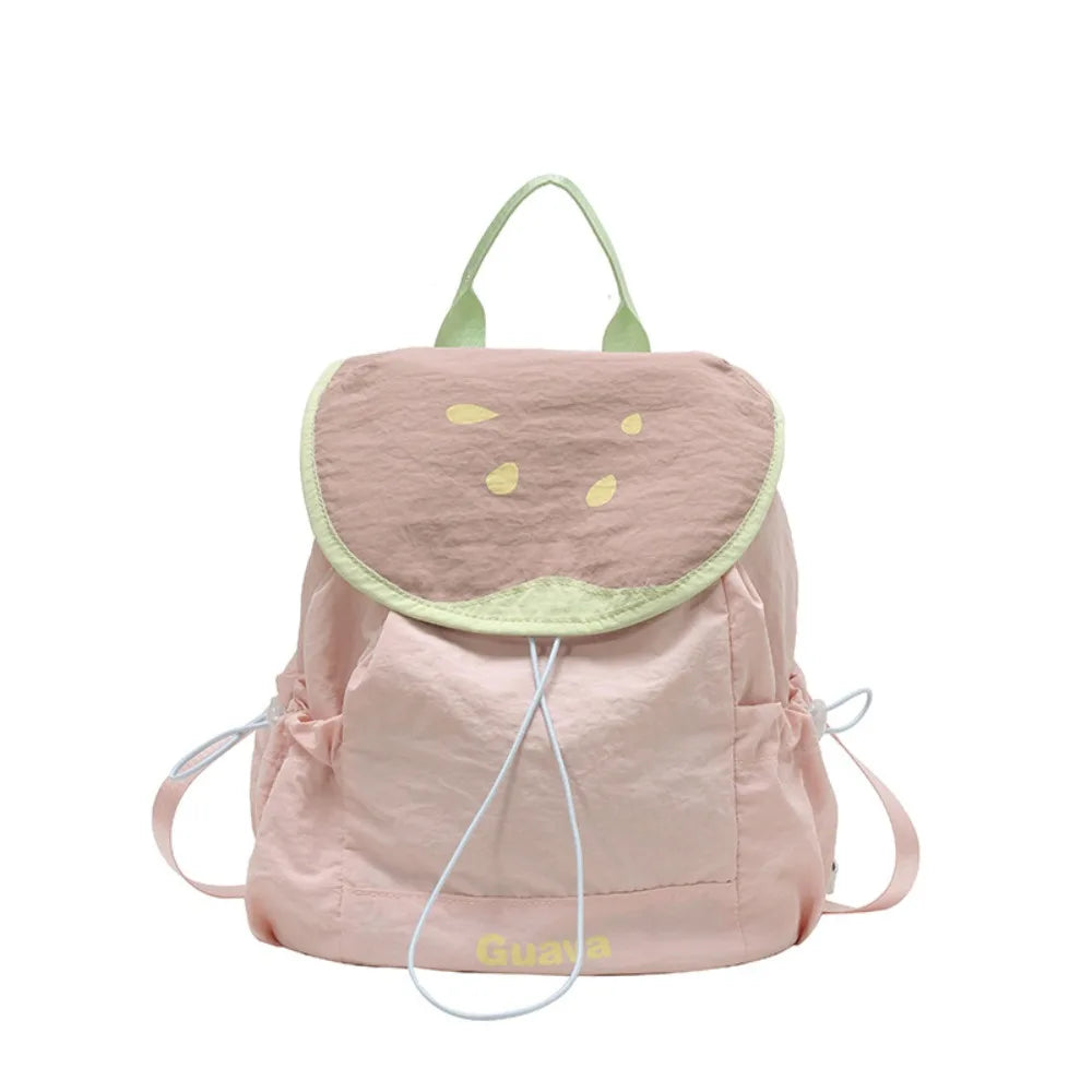 A light pink nylon messenger backpack with a green trim and yellow embroidered fruit design.