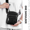 A black vintage leather messenger bag is shown being held by a person against a white shirt.