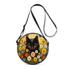 A round black cat illustration on a yellow floral background, attached to a black strap.