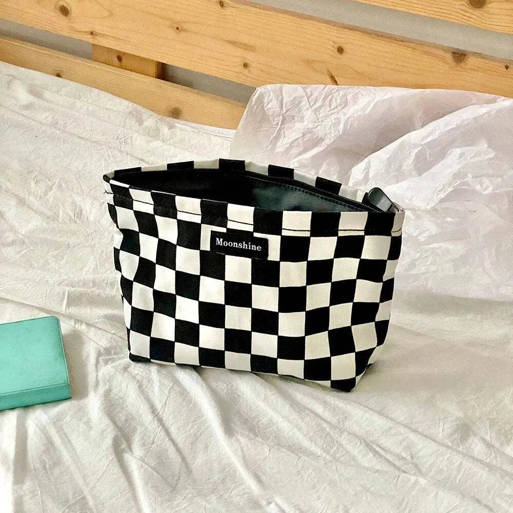 A black and white checkered cosmetic storage bag with the brand name Moonshine resting on a white surface.