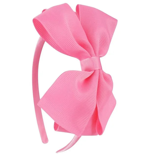 A pink ribbed fabric bow headband is shown against a white background.