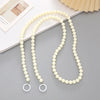 A necklace made of small, creamy white acrylic beads with silver-colored charms.