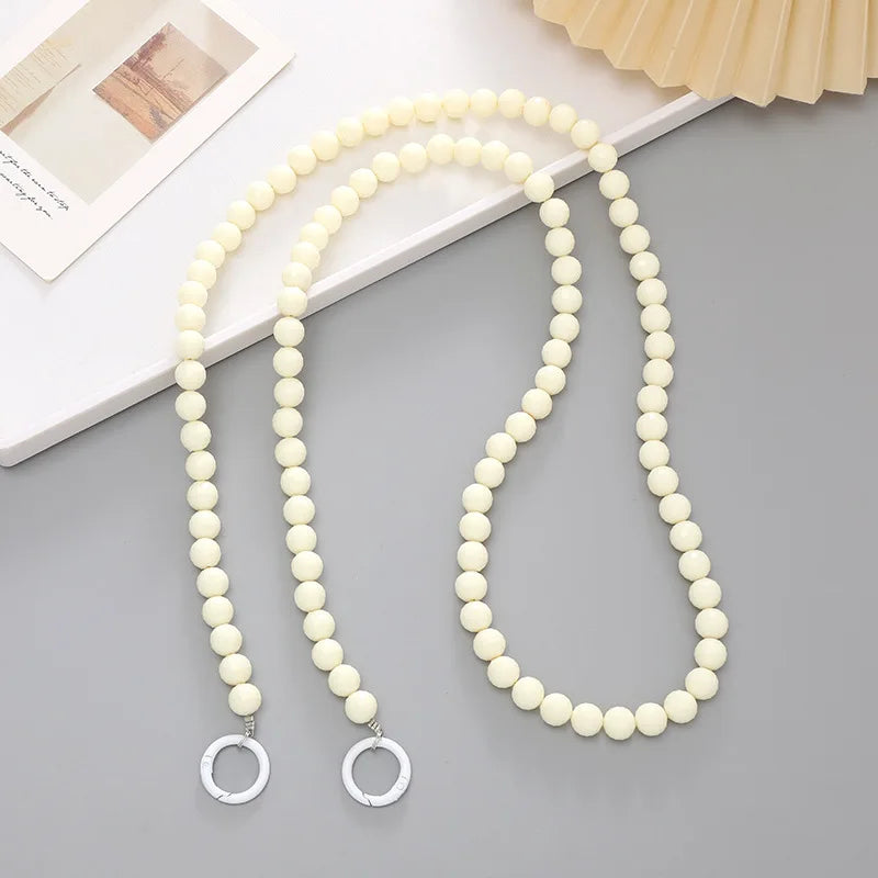 A necklace made of small, creamy white acrylic beads with silver-colored charms.