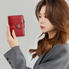 A woman holds a red leather multi-fold wallet in her hand against a light gray background.