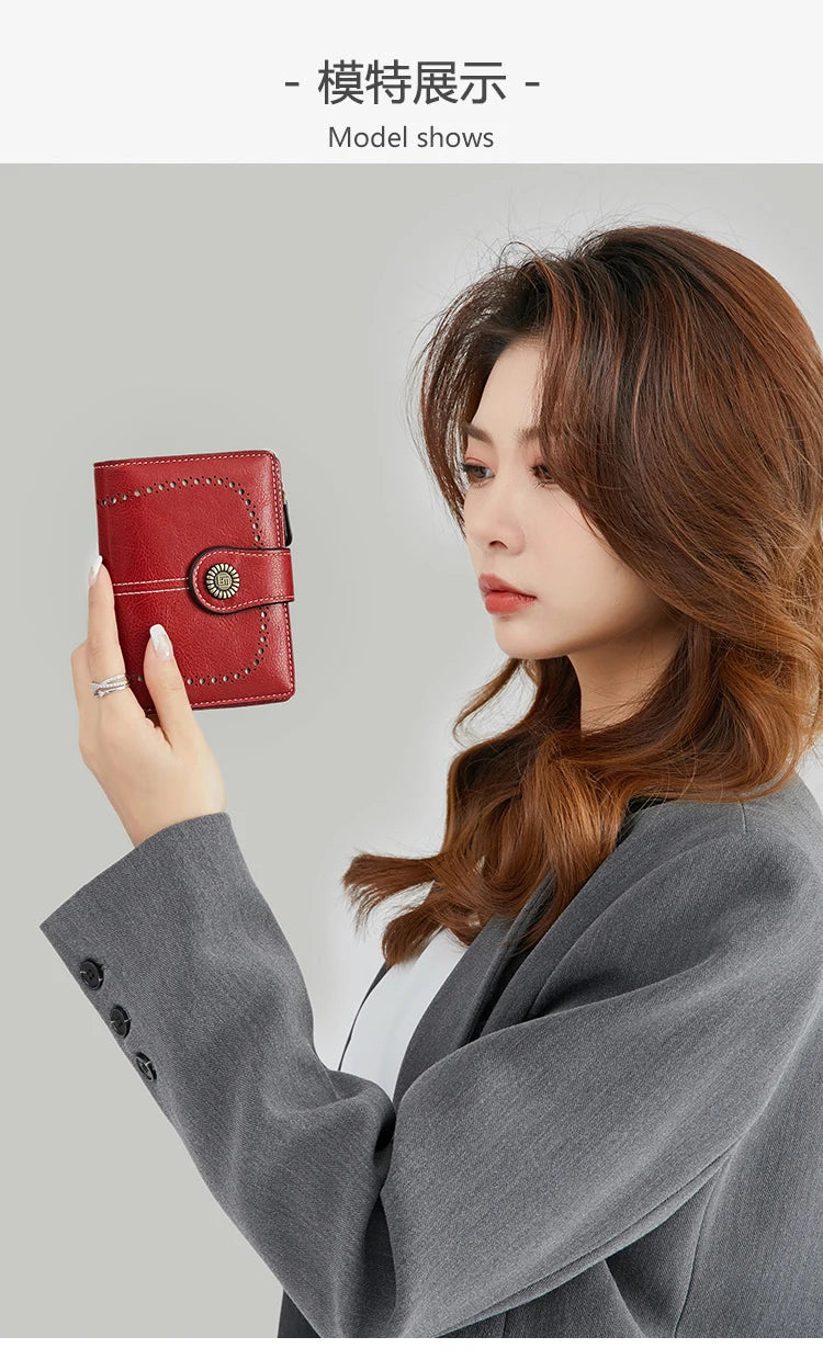 A woman holds a red leather multi-fold wallet in her hand against a light gray background.