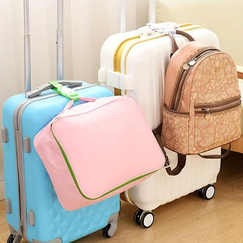 A light blue rolling suitcase is shown next to a cream-colored suitcase with tan straps.