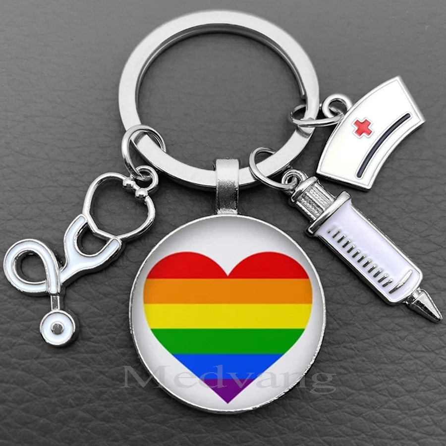 Silver keychain featuring a heart design with the Pride rainbow flag and a medical syringe charm