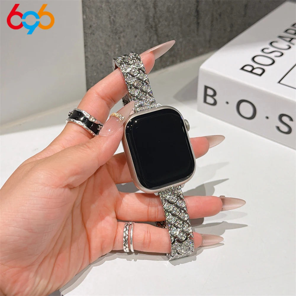 A hand is wearing a sparkling metal strap Apple Watch band with crystal fishscales on a black watch face.