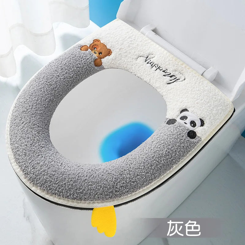 A plush waterproof toilet seat cover with a gray texture and a panda design is shown inside a white toilet bowl.