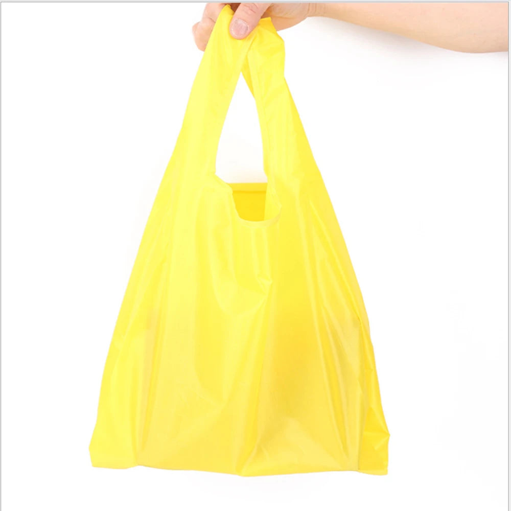A hand is holding a bright yellow eco-friendly foldable shopping bag.