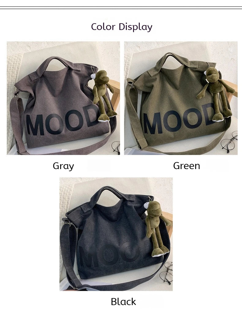 Three canvas tote bags in gray, green, and black featuring a mood design and a small figurine.