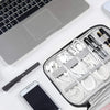 A silver laptop, a black pen, and a gray travel cable organizer pouch with various electronic accessories are shown on a whit