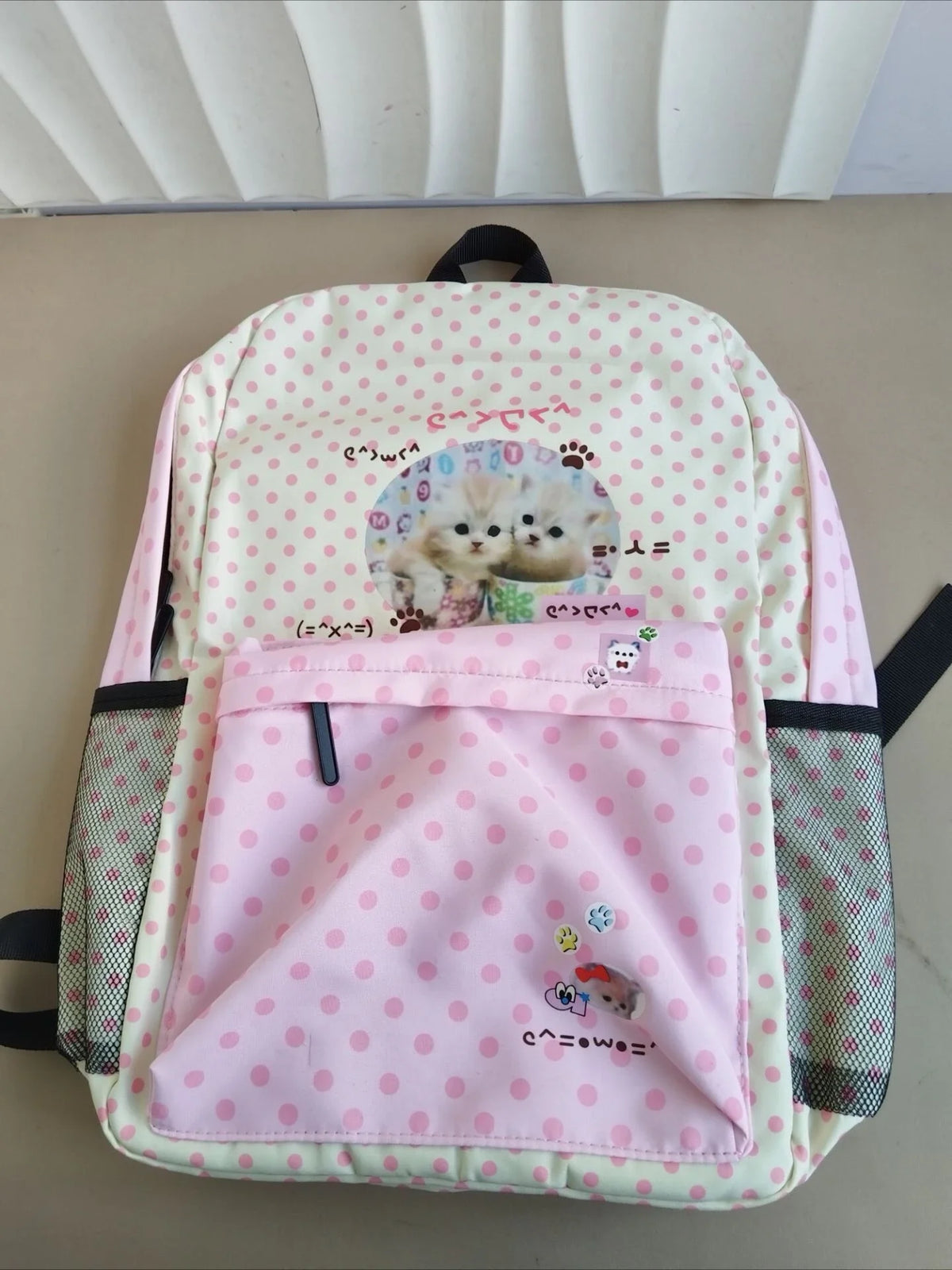 Sac à dos à motifs rose et vert avec un design de chat sur la poche avant.