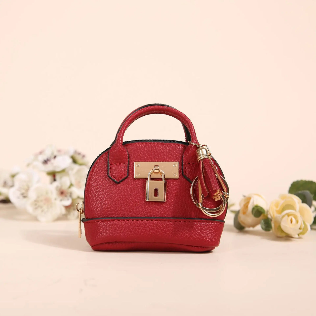 Portefeuille en cuir rouge profond avec fermoir et chaîne dorée, posé sur une surface claire.