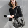 Eine Frau modelliert eine Vintage-Soft-PU-Leder-Schultertasche mit einem schwarzen Pullover und weißen Hosen.