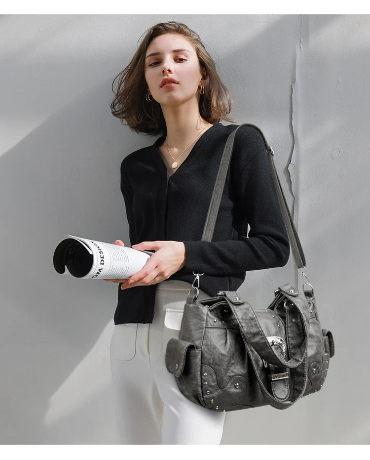 Eine Frau modelliert eine Vintage-Soft-PU-Leder-Schultertasche mit einem schwarzen Pullover und weißen Hosen.