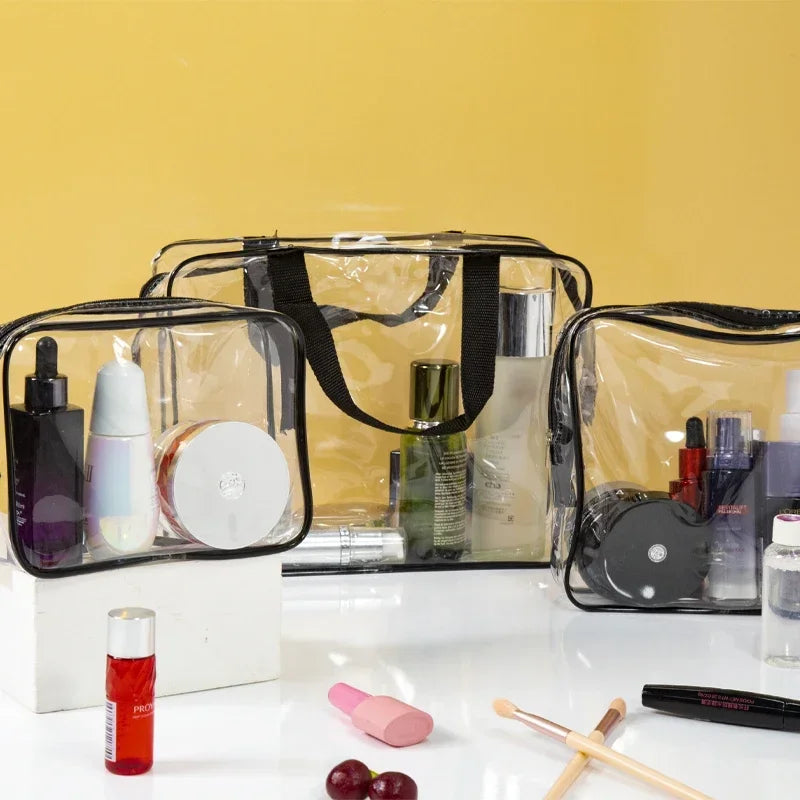 A set of three clear PVC travel toiletry bags with black straps and various toiletries displayed on a white surface.