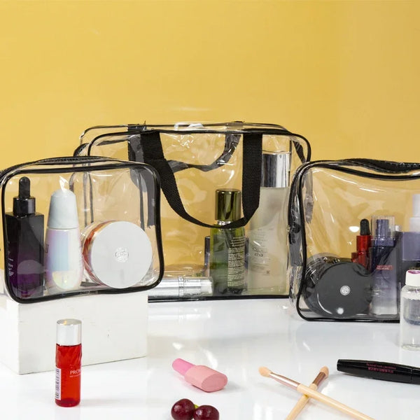 A set of three clear PVC travel toiletry bags with black straps and various toiletries displayed on a white surface.