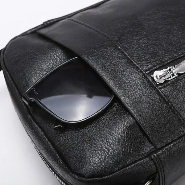 Black waterproof PU leather sling bag featuring a clear lens case and silver zipper detail.