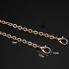 Gold-toned metal chain strap with adjustable links and oval clasps shown against a black background.